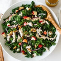 Kale salad recipe in a serving bowl with wooden serving spoons.