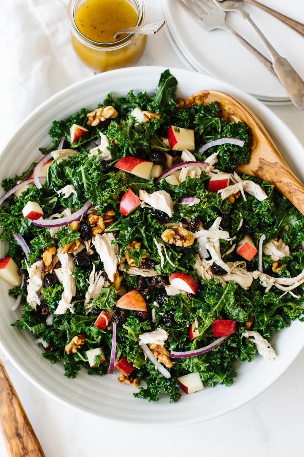 Kale salad with apples and chicken is bursting with autumn flavors in every single bite! Kale salad with chicken and apples on a white table