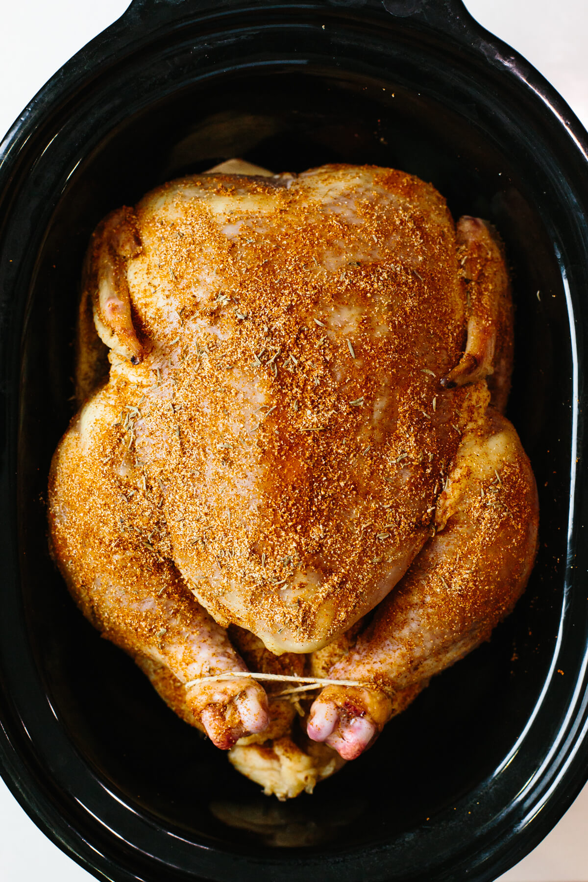 Chicken rubbed with herbs in slow cooker.