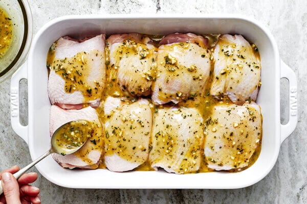 Pouring honey mustard marinade over chicken thighs