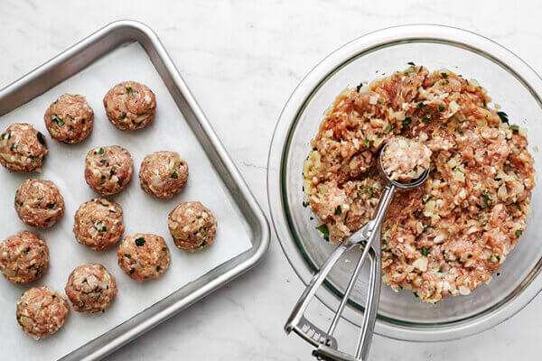 Rolling fennel pork meatballs onto a sheet pan