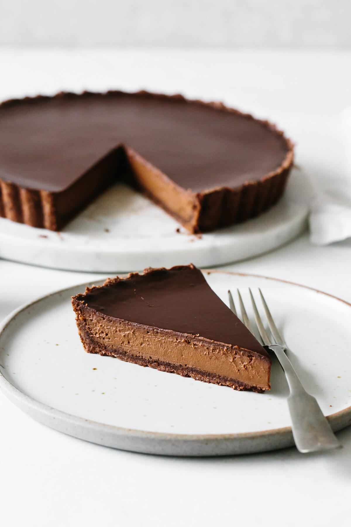 A single slice of chocolate tart on a plate.