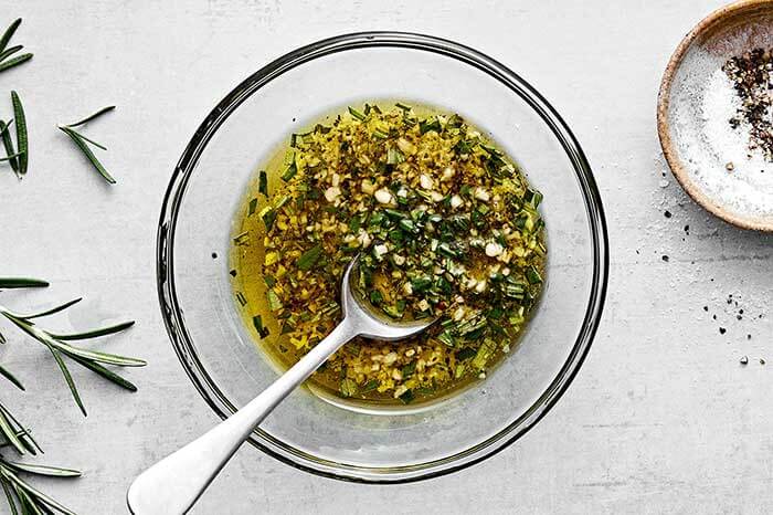 Lamb chop marinade in a bowl with rosemary and garlic.
