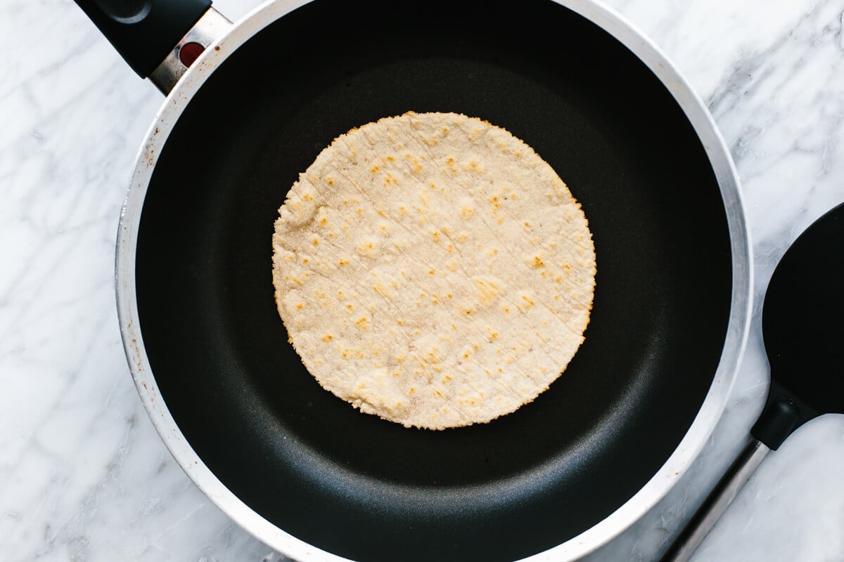 A pan cooking a cassava flour tortilla