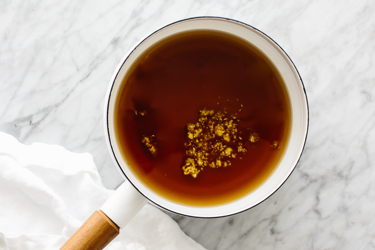 Infusing the maple syrup with grated ginger in a pot.