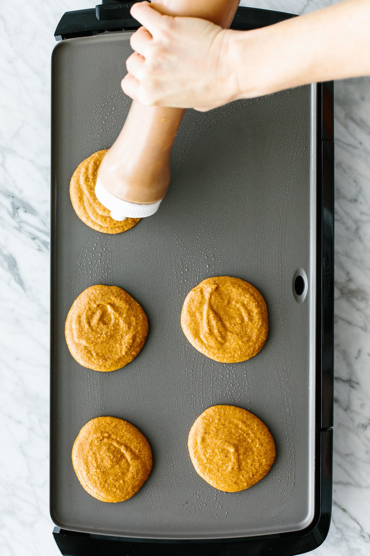 Pouring the pancake batter onto an electric skillet.