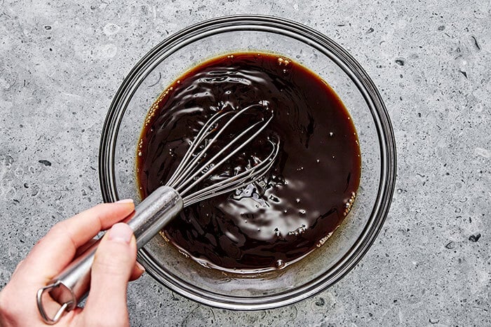 Whisking brisket braising liquid in a bowl.