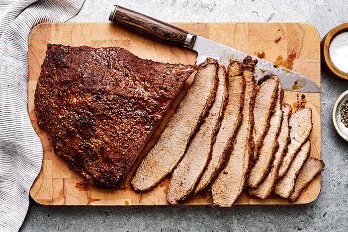 Sliced beef brisket on a wooden board.