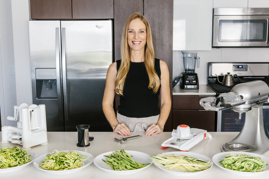 Lisa in her kitchen with several plates of zucchini noodles.