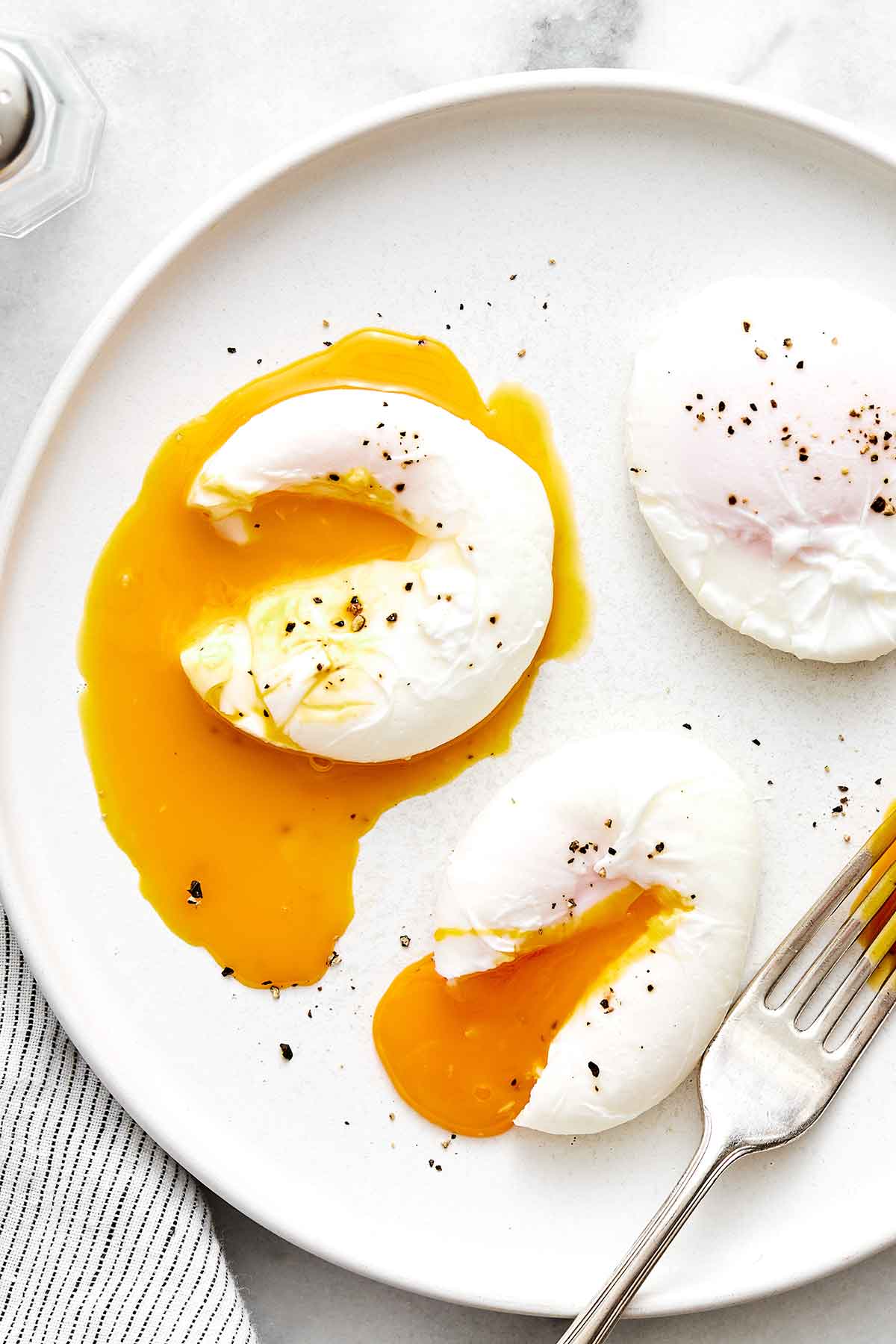 Learn how to make perfect poached eggs every time with this easy method! It'll be a delicious addition to a healthy breakfast. Poached eggs on a plate.