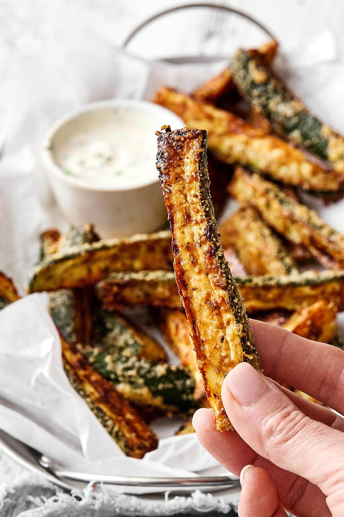 Holding a baked zucchini fry.