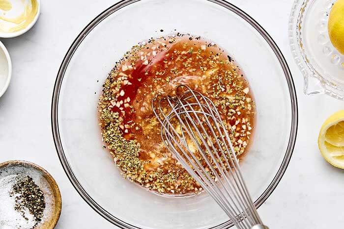 Using a whisk to make Greek salad dressing.
