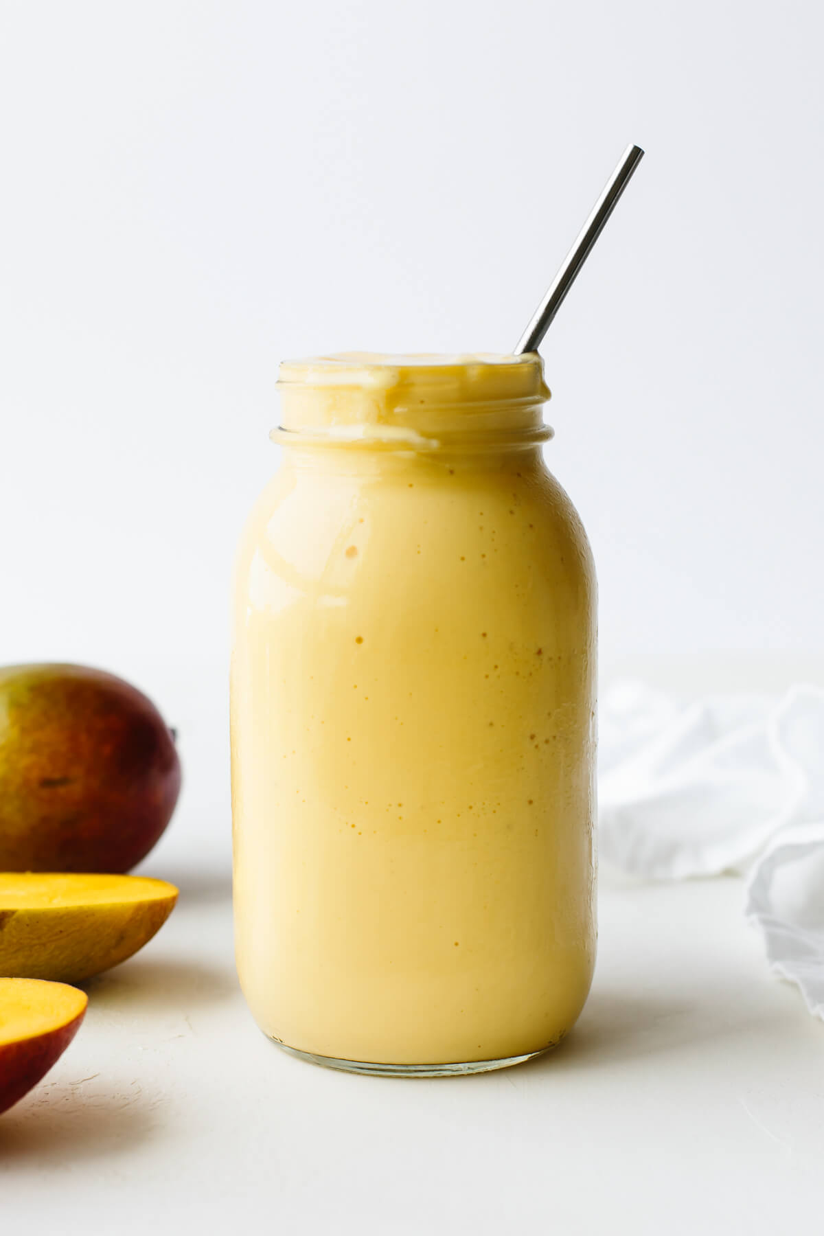 This creamy mango smoothie recipe is just the ultimate summer thirst quencher! Mango smoothie in a mason jar