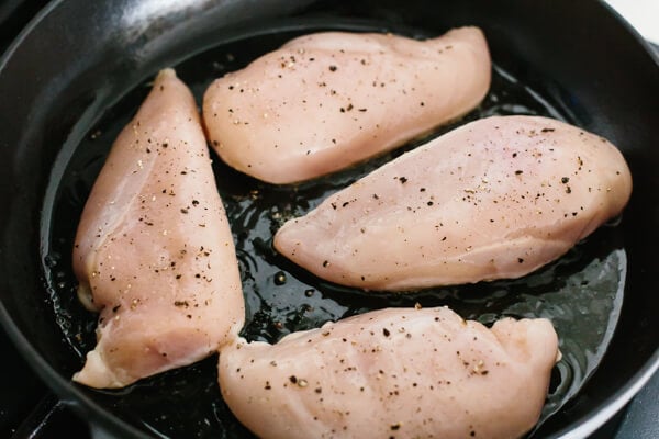 Chicken breasts searing in a pan.