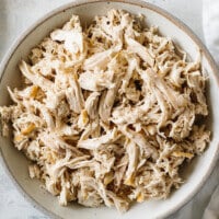 A bowl of shredded chicken on a table.