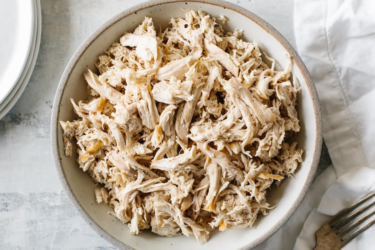 A bowl of shredded chicken on a table.