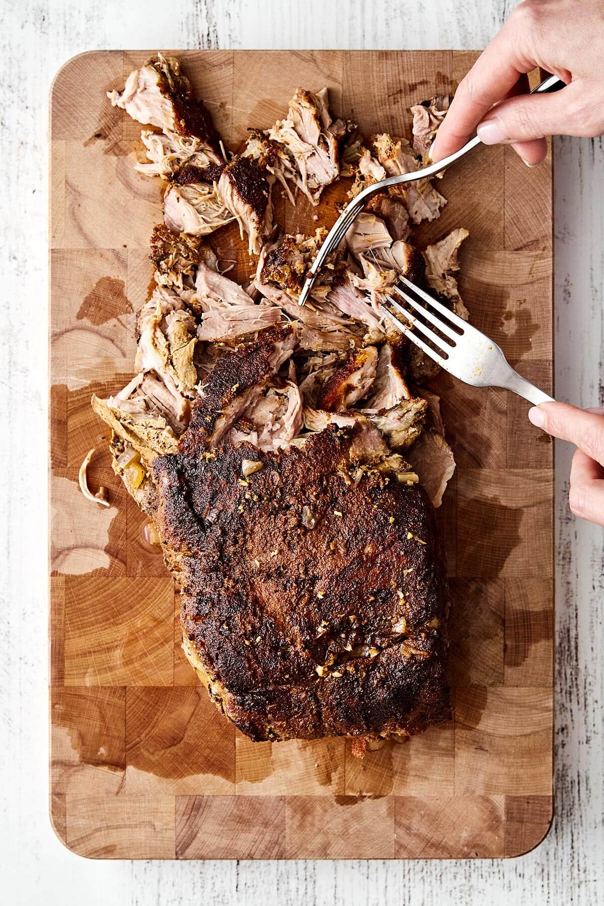 Shredding pulled pork on a board.