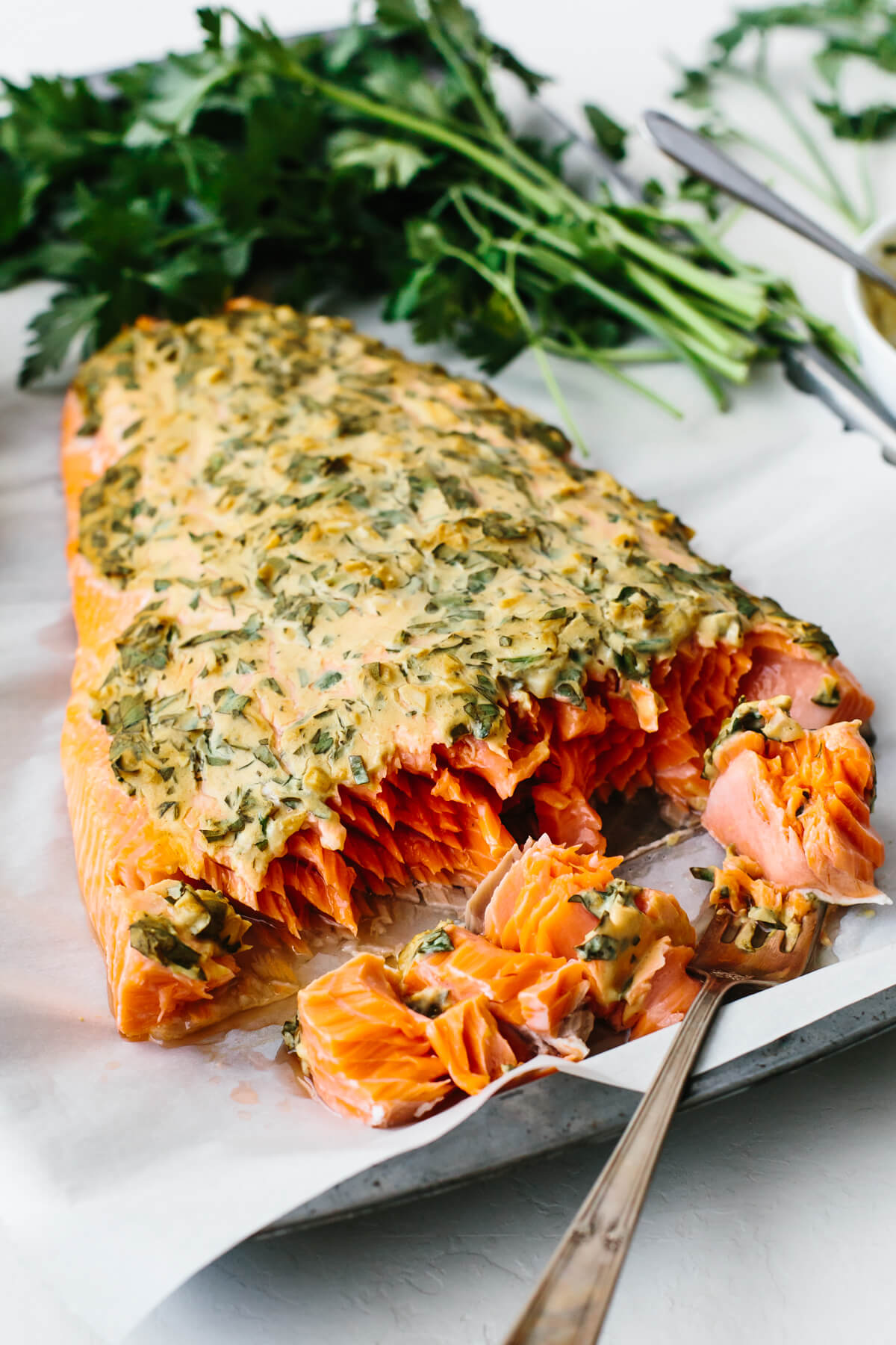 This dijon baked salmon is incredibly flavorful, moist, flaky, and a healthy dinner recipe that’s made in under 30 minutes! A piece of dijon baked salmon next to parsley.