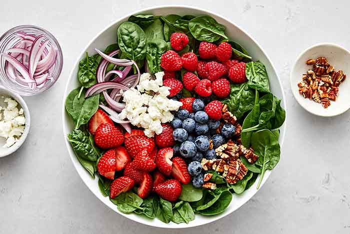 Making berry spinach salad recipe.