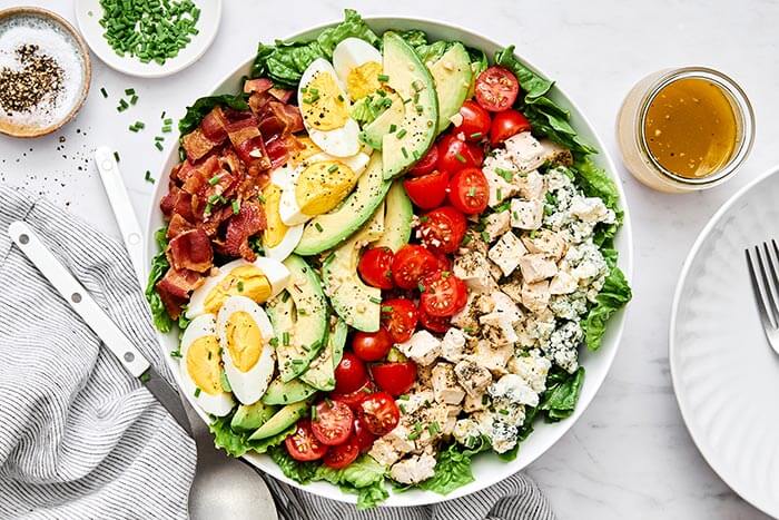 A bowl of Cobb salad next to a napkin.