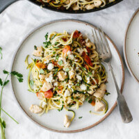 Zucchini noodles with chicken and pico de gallo on a white plate.