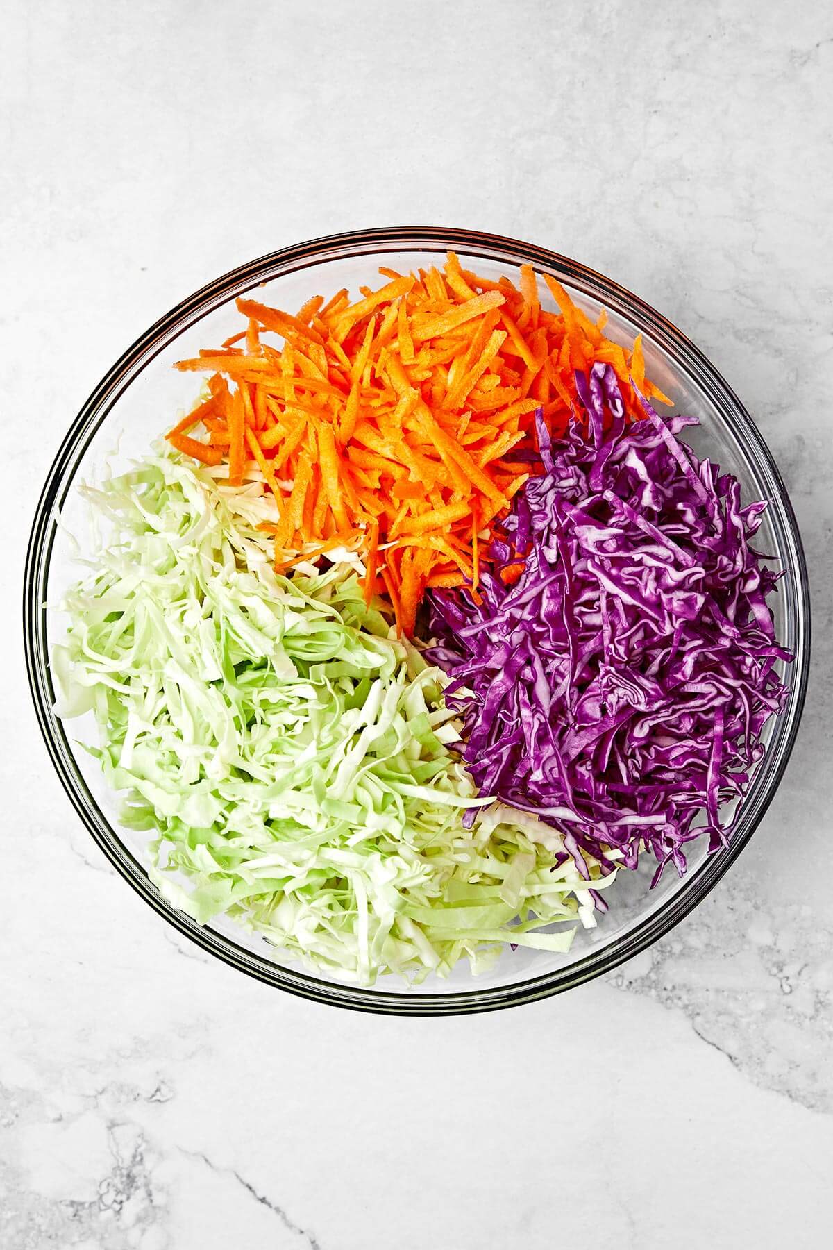 This easy coleslaw recipe is perfect for summer BBQ's and potlucks, whether it's served as a side dish or layered in pulled pork sliders! Shredded coleslaw ingredients in a bowl.