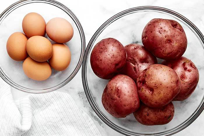 Cooled potatoes and eggs in bowls.
