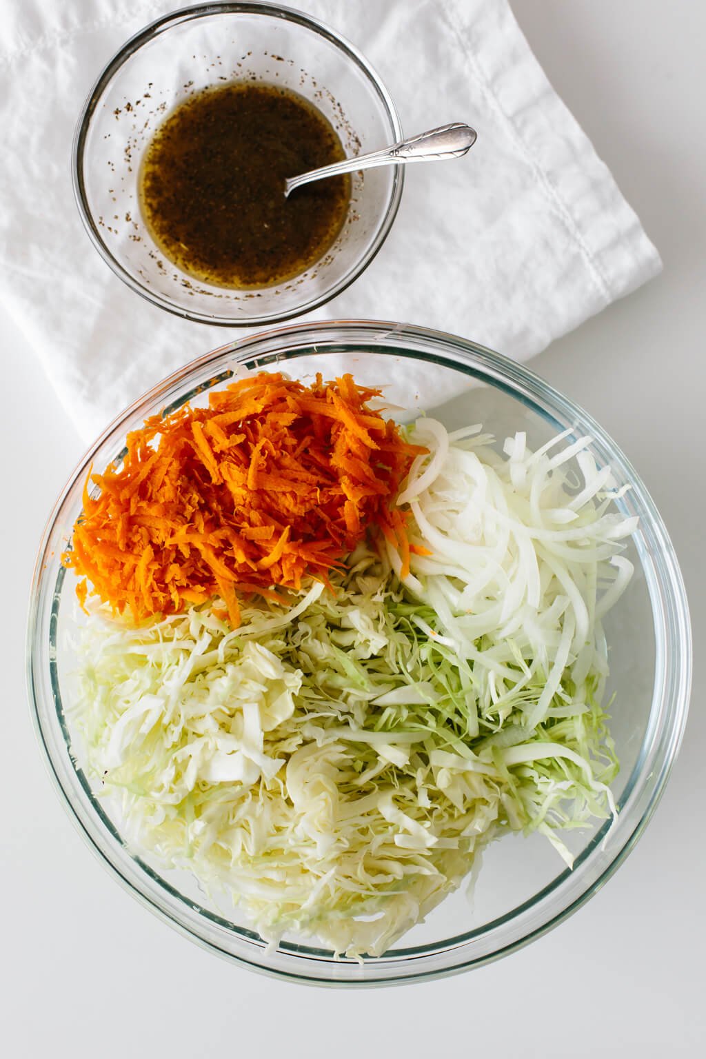 Vinegar coleslaw ingredients in a mixing bowl with dressing on the side.