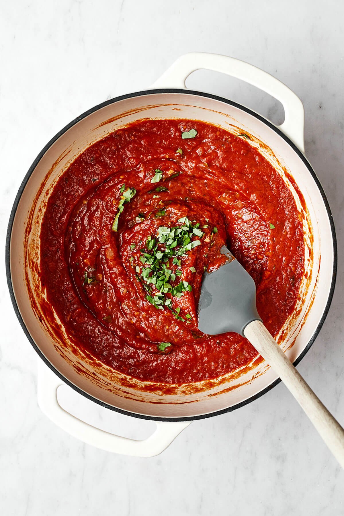 Stirring basil into marinara sauce