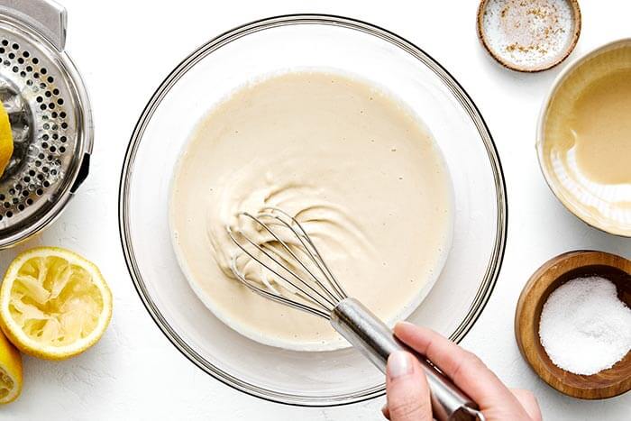 Whisking tahini sauce in a bowl.