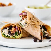 Healthy chicken wrap cut in half on a white plate.