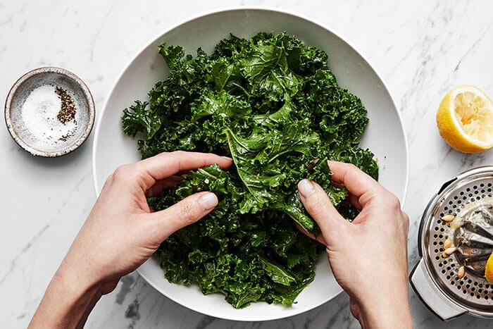 Massaging kale in a bowl.