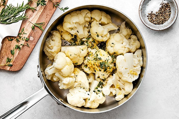 Mixing cauliflower and herbs in a pot.