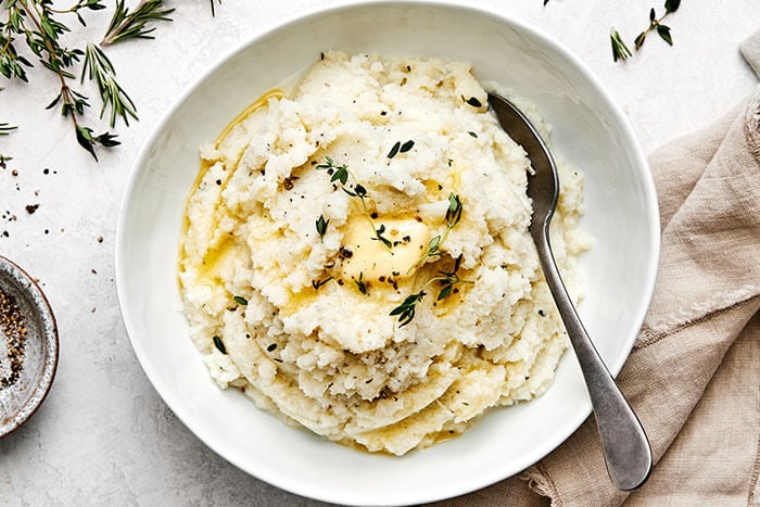 A white bowl of mashed cauliflower.