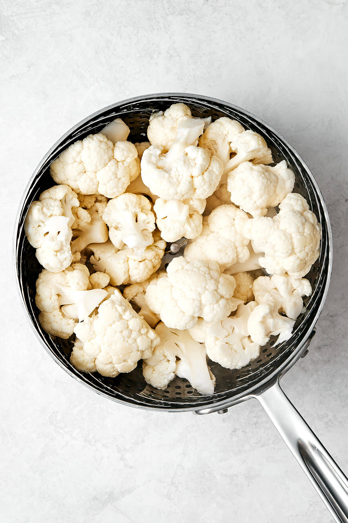 This mashed cauliflower is a fabulous low-carb side dish for weeknight dinners. It's delicious, creamy, flavorful, and quick to make! Boiling cauliflower in a pot.