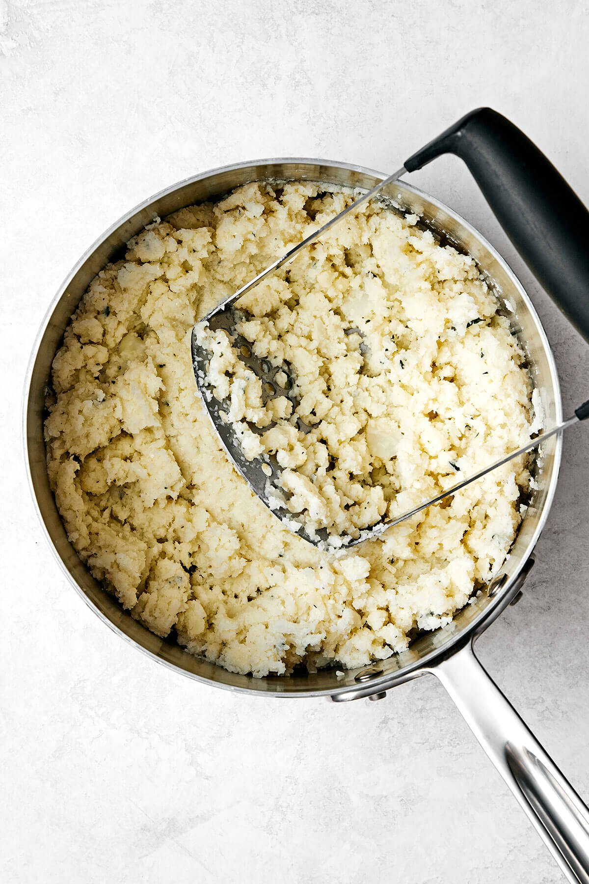 This mashed cauliflower is a fabulous low-carb side dish for weeknight dinners. It's delicious, creamy, flavorful, and quick to make! Mashing cauliflower in a pot.