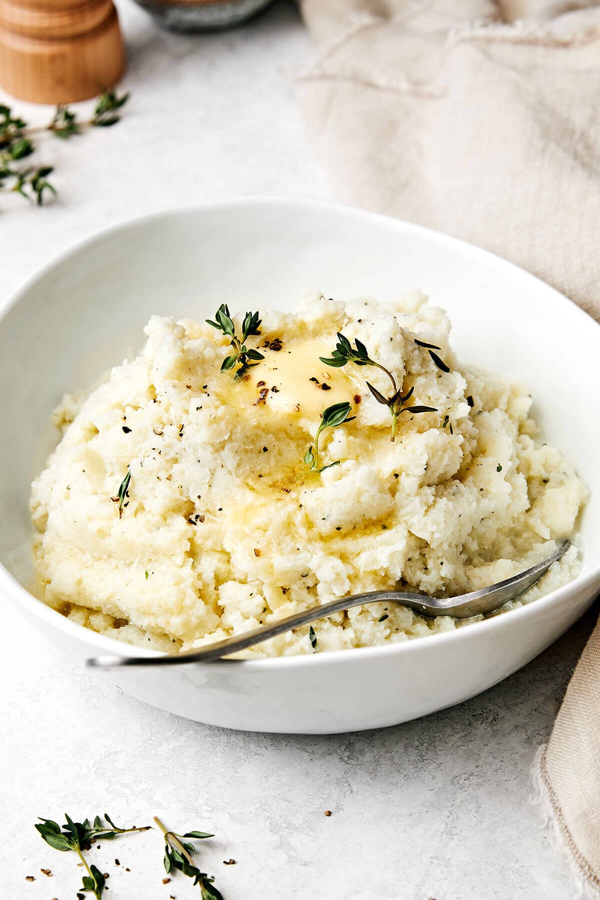 This mashed cauliflower is a fabulous low-carb side dish for weeknight dinners. It's delicious, creamy, flavorful, and quick to make! A bowl of mashed cauliflower with a spoon.