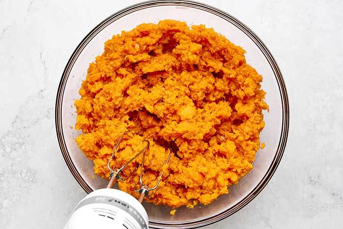 Blending sweet potatoes in a bowl.