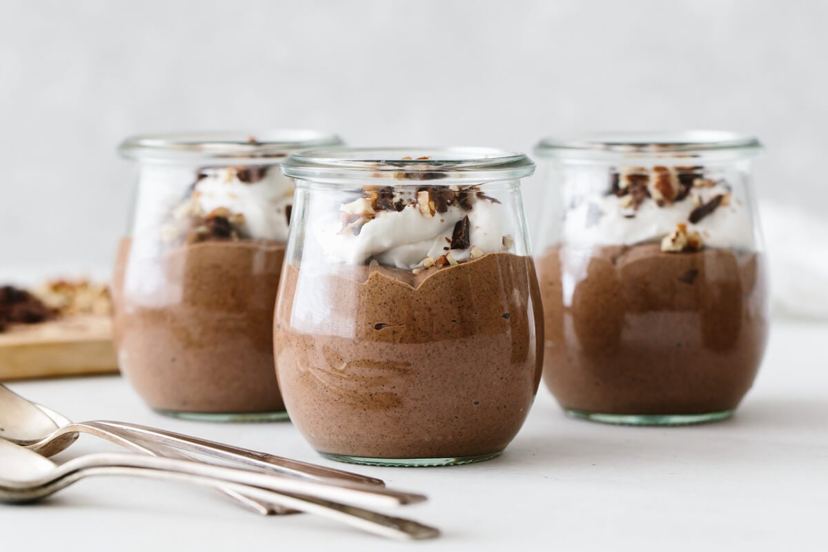 Three servings of chocolate chia pudding mousse with toppings.
