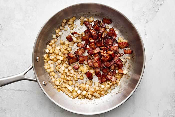 Cooked onion and bacon in a pan.