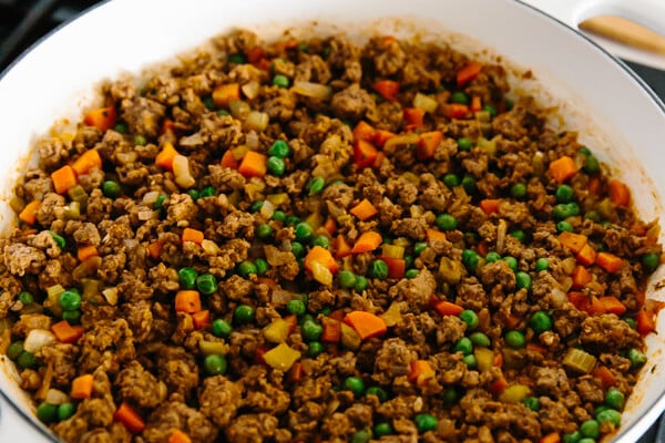 Mixing spices into the Shepherd's pie filling on the stove.
