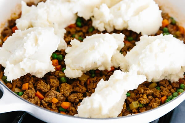 Dolloped mashed potatoes on top of the Shepherd's pie filling ingredients.