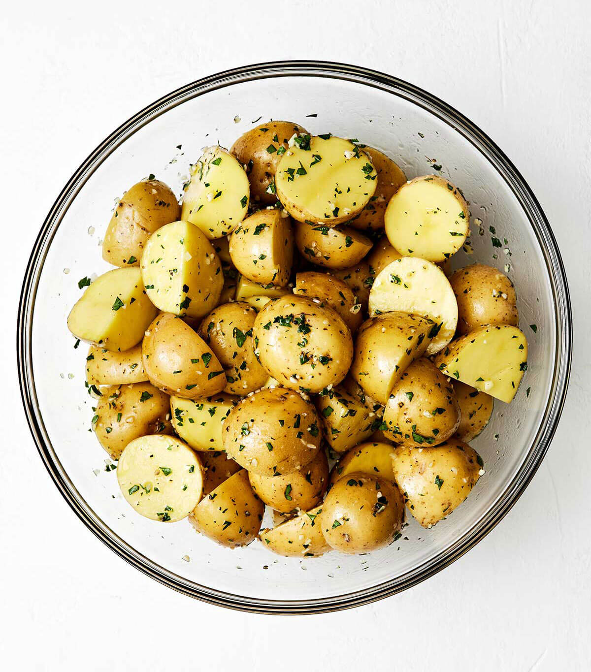 A bowl of uncooked garlic roasted potatoes.