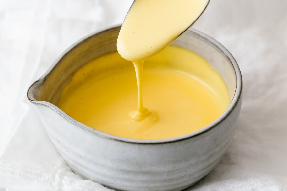 Hollandaise sauce is a classic creamy sauce that's perfect for brunch and comes together with 5 simple ingredients. It's easy in a blender! Hollandaise sauce dripping off a spoon.