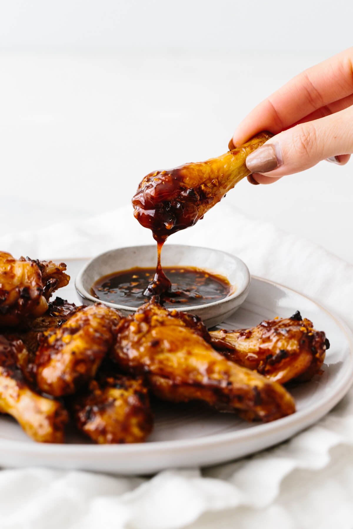 A chicken wing dipping in soy garlic ginger sauce. 