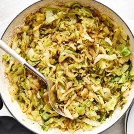 Sauteed cabbage in a pan with a spoon.