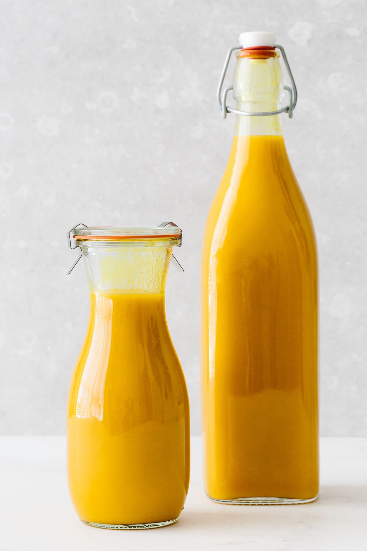 Jamu juice is an Indonesian anti-inflammatory drink that's a blend of fresh turmeric, ginger, lemon, water, and honey. Jamu juice in two glass storage containers.