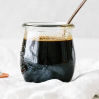 Teriyaki sauce in a glass jar with a spoon.