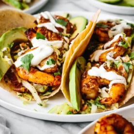 Two shrimp tacos on a plate with cilantro lime slaw.