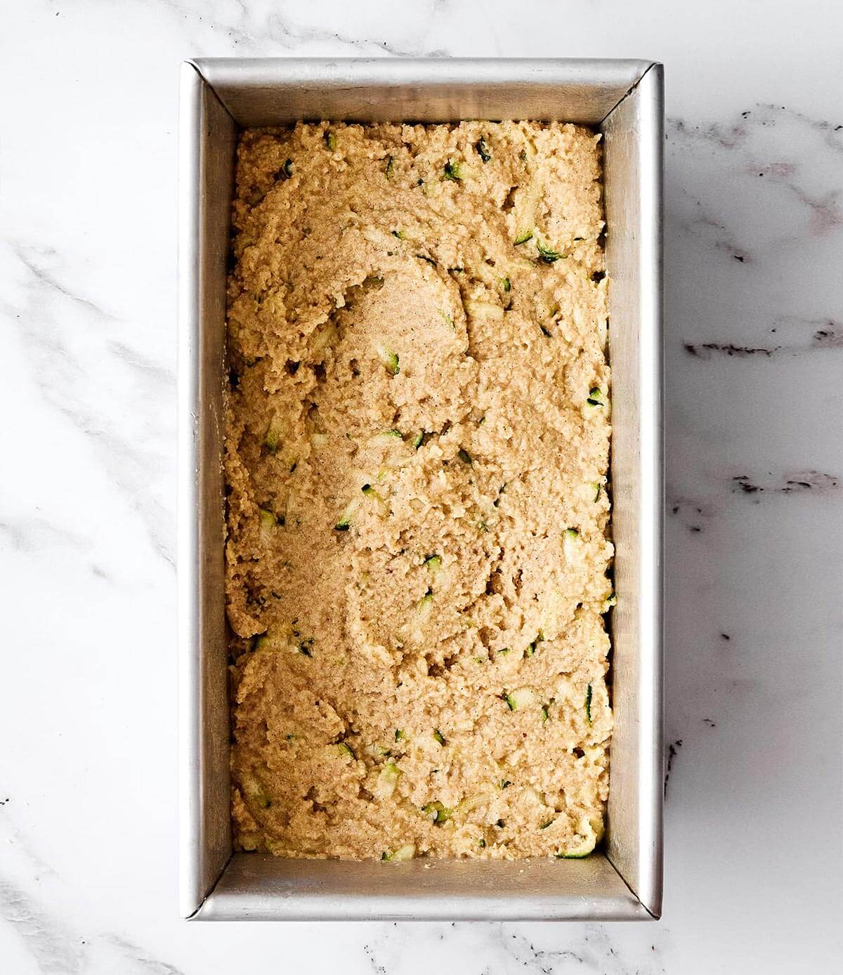 Creating a zucchini bread loaf.